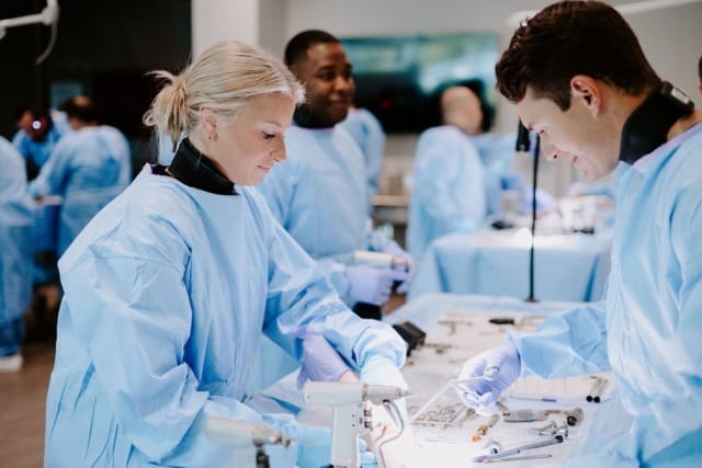 Medical professionals in blue scrubs performing surgical procedures in a hospital room with various instruments.